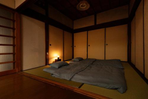 a large bed in a room with a lamp at 古民家一棟貸 鴨部巣 kamobese in Kochi