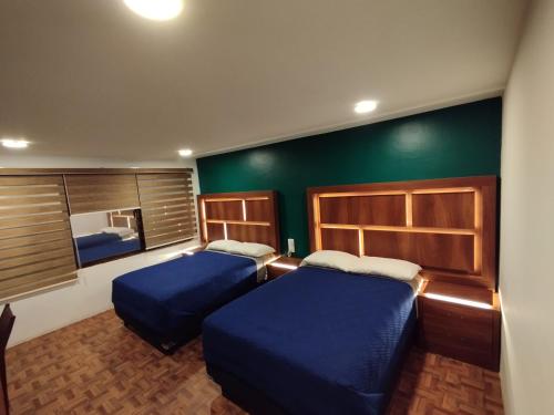 two beds in a room with green walls at Posada Familiar Lupita in Texcoco de Mora