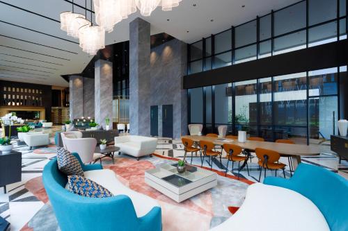 a lobby with blue chairs and a table and chairs at Harris Hotel & Convention Serpong in Tangerang