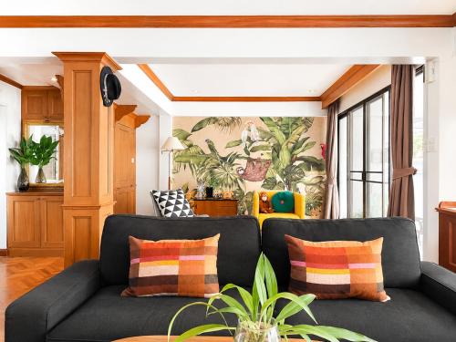 a living room with a black couch with colorful pillows at Pannarai's House in Bangkok