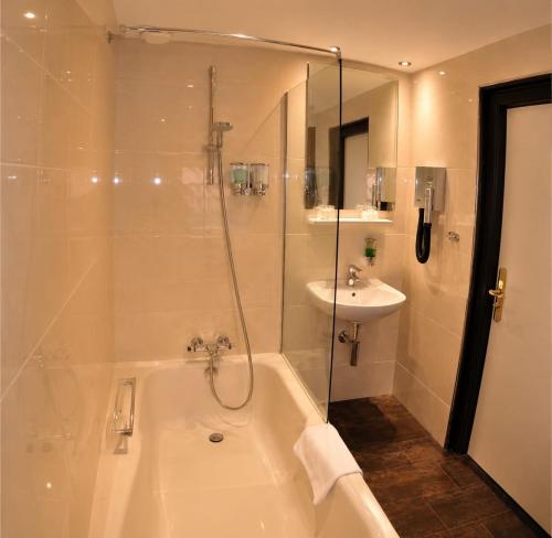 a bathroom with a shower and a tub and a sink at Budget Hotel Le Beau Rivage in Middelburg