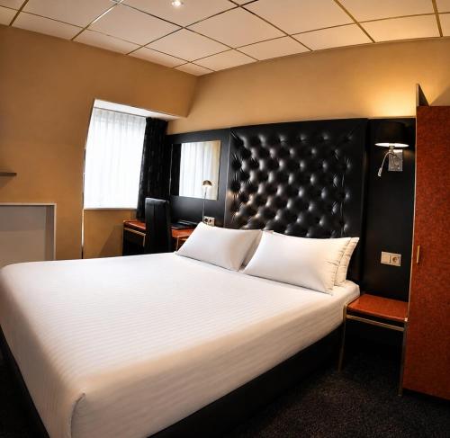 a bedroom with a large white bed with a black headboard at Budget Hotel Le Beau Rivage in Middelburg