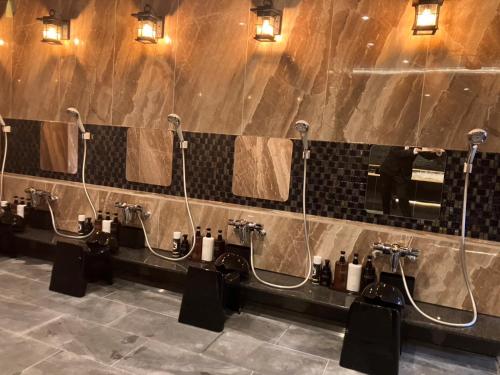 a bathroom with a row of urinals and sinks at Hotel LiVEMAX Tendo in Tendo