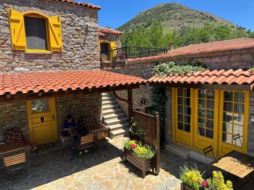 a building with yellow doors and a person sitting on a bench at Ilios Guest House in Gokceada Town