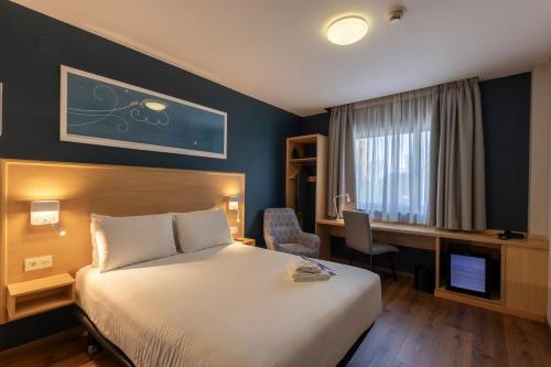 a hotel room with a bed and a desk and a television at Travelodge Madrid Arturo Soria in Madrid