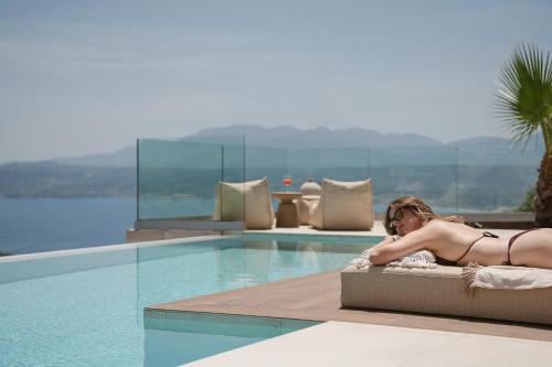 a woman laying on a bed next to a swimming pool at Villa Niolos II in Stérnai