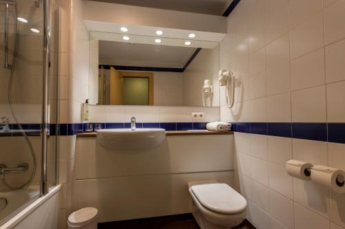 a bathroom with a sink and a toilet and a mirror at Travelodge Madrid Arturo Soria in Madrid