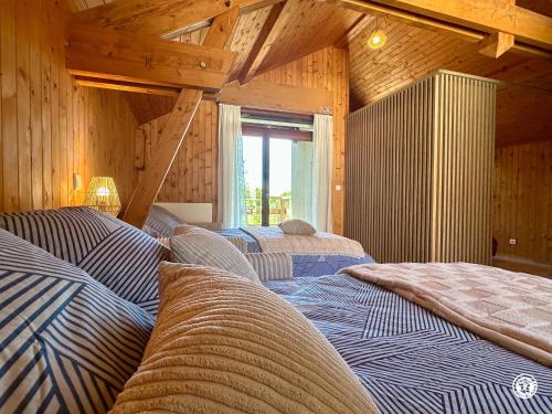 three beds in a room with wooden walls at Gîte des Pruniers in Saint-Germain-le-Rocheux