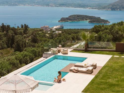 a woman sitting next to a swimming pool at Villa Niolos II in Stérnai