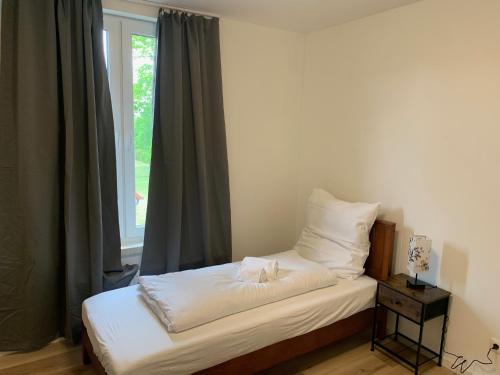 a bed with white sheets and pillows in front of a window at Apartments Adelheid in Wathlingen