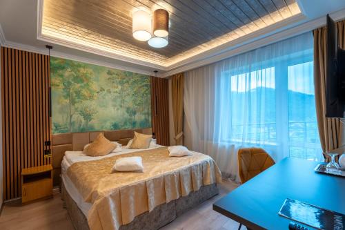 a bedroom with a bed and a desk and a large window at Pensiunea Warthe Bed & Breakfast in Braşov