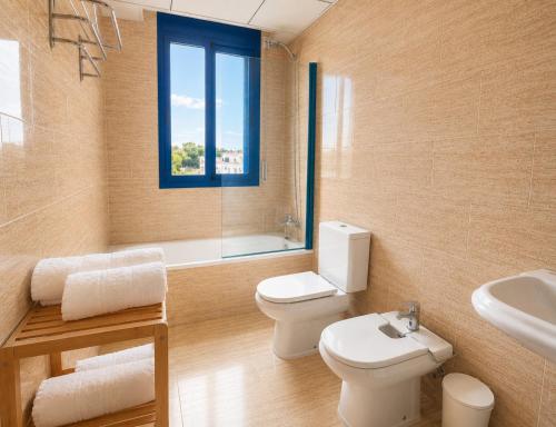 a bathroom with a toilet and a sink and a window at Casa 3 hab, piscina, playa, parking, L'Ampolla in L'Ampolla
