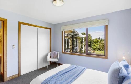 a bedroom with a bed and a window and a chair at Peninsula Paradise in Dunedin