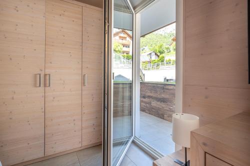 a glass pivot door in a kitchen with wooden walls at Molveno Garden Suite in Molveno