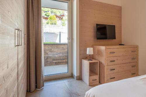 a bedroom with a bed and a tv and a window at Molveno Garden Suite in Molveno