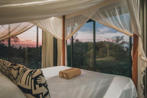 a bedroom with a bed with a large window at Mangroove Bay Boutique Hostel in Banyuwedang