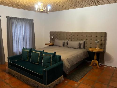 a bedroom with a bed and a green couch at The Old Posthouse in Ladismith