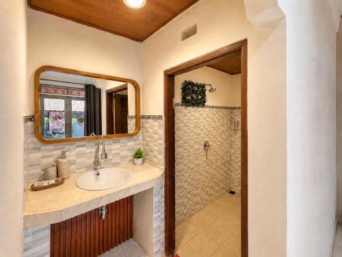 a bathroom with a sink and a shower with a mirror at Purnama House Ubud in Ubud