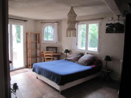 a bedroom with a bed and a table and windows at Lou Mazet - Entre Vignes et Garrigue in Valflaunès