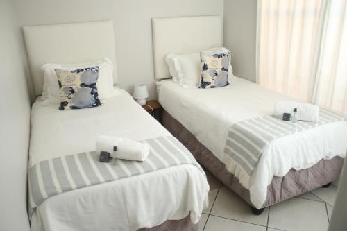 two beds in a room with white and blue pillows at Gemutlich Guesthouse in Upington