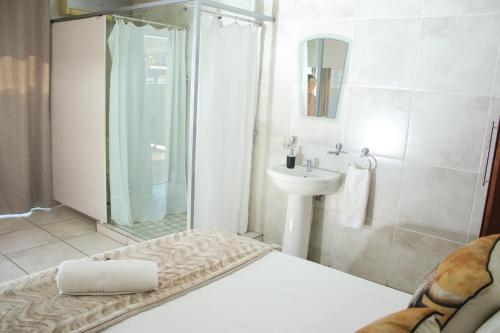 a bathroom with a bed and a sink and a shower at Gemutlich Guesthouse in Upington