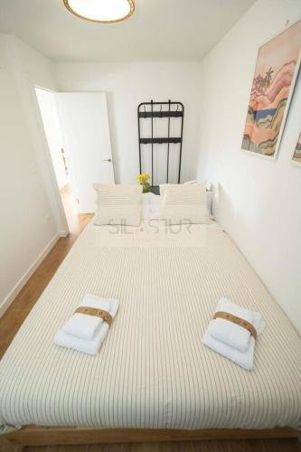 a large white bed with two white towels on it at Los Sauces By Silastur in Villaviciosa