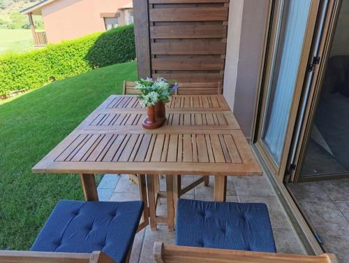 a wooden picnic table with two chairs and a vase of flowers at Planta baja con jardín en Llívia in Llivia