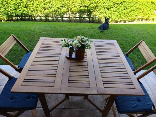 a wooden table with two chairs and a dog at Planta baja con jardín en Llívia in Llivia