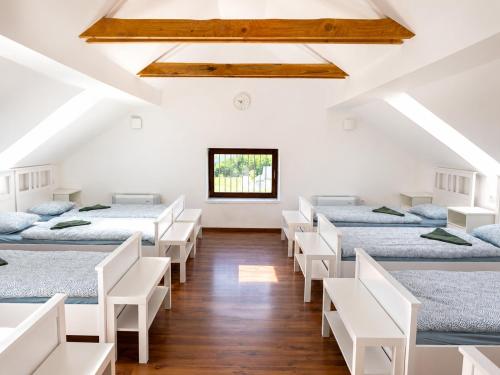 a room with four beds and white chairs at HOSTEL VANEČA in Puconci