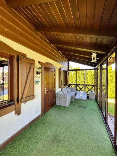 a screened in porch with a couch and windows at Lesne Domki VIP in Prokowo