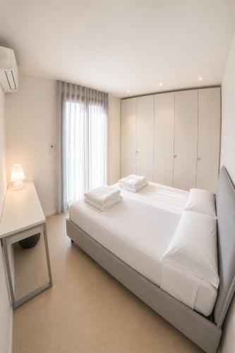 a white bedroom with a large bed and a table at Suite Serenissima bilocale con terrazzo frontemare - Agenzia Cocal in Caorle