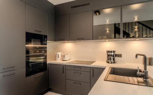 a kitchen with white cabinets and a sink at Słoneczne Tarasy in Rewal