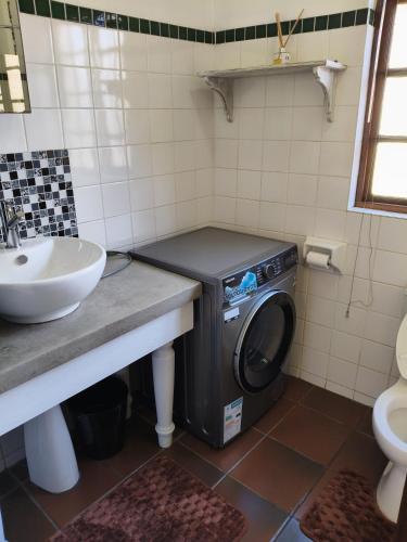 a washing machine in a bathroom next to a sink at The Museum Cottage in Sabie