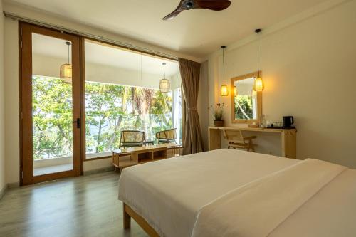 ein Schlafzimmer mit einem großen weißen Bett und einem Fenster in der Unterkunft Odi Beachfront Kamadhoo in Kamadhoo