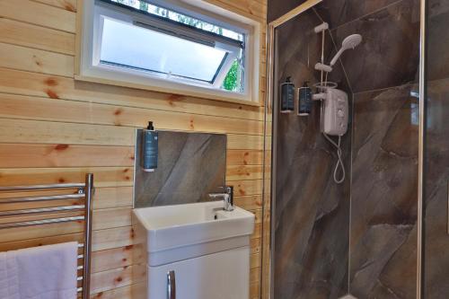 a bathroom with a sink and a shower with a window at Great Hallingbury Lodges in Hallingbury