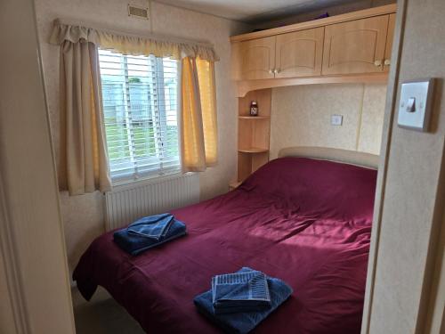 a small bedroom with a red bed with towels on it at Julie and Shaun's in Ingoldmells