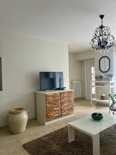 a living room with a flat screen tv and a table at Corps de ferme à 50min de Lyon in Moissieu-sur-Dolon