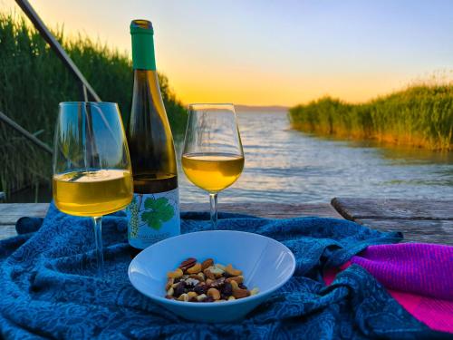 a table with two glasses of wine and a bowl of nuts at Angele Pihenőház in Balatonszárszó