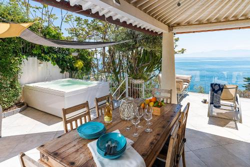 a wooden table with chairs and a hot tub on a patio at Casa Mamà private access to sea in Santa Flavia