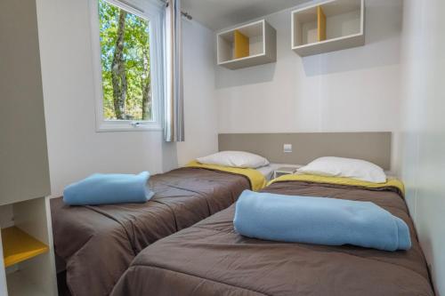 three beds sitting in a room with a window at Camping Le Parc in Saint-Paul-en-Forêt