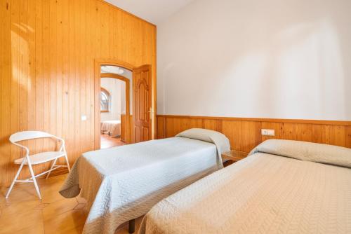 a bedroom with two beds and a chair in it at Ca la Crish in Horta de San Joan