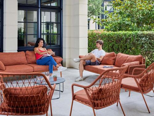 a man and woman sitting on chairs on a patio at Adagio Serris Val d'Europe in Serris