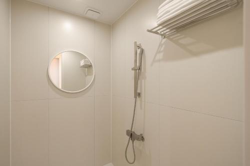 a white bathroom with a shower and a mirror at No25 Hotel Chuncheon Cityhall in Chuncheon