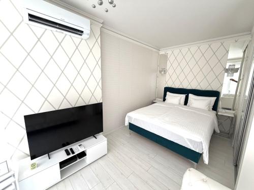 a bedroom with a bed and a flat screen tv at Cloé Apartman by Noir Hotel in Szeged
