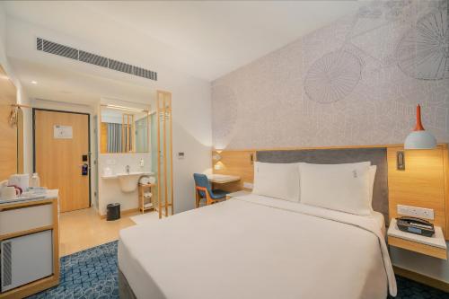a hotel room with a large white bed and a desk at Holiday Inn Express Gurugram Sector 50 by IHG in Gurgaon