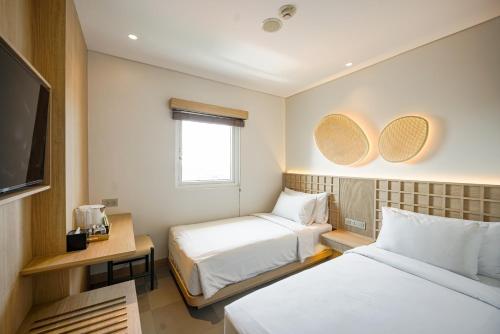 a hotel room with two beds and a tv at Kotta Kyu Hotel Semarang in Semarang