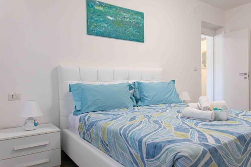 a white bedroom with a bed with blue pillows at Casa Turchese in Alghero