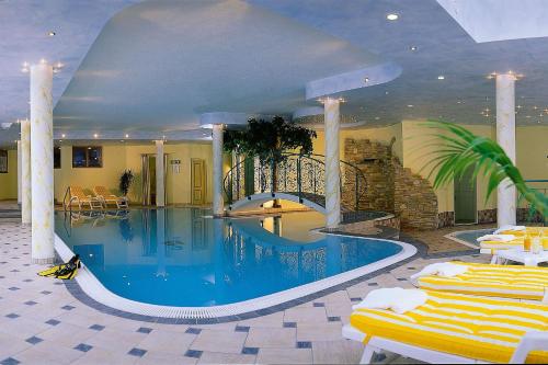 a large swimming pool in a hotel with yellow chairs at Family Apart Stubai in Fulpmes