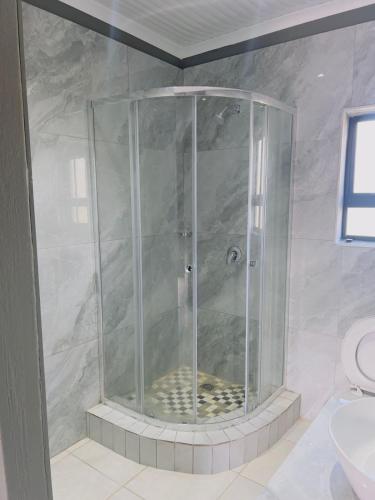 a shower with a glass door in a bathroom at Mangena Legacy Guesthouse in Polokwane