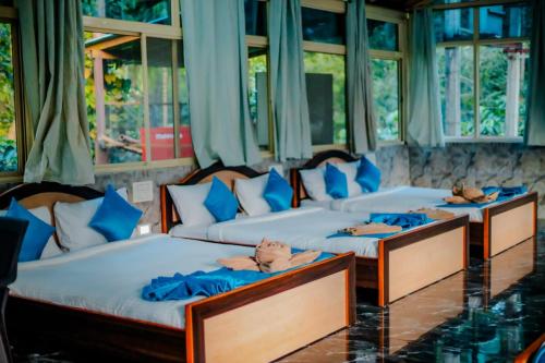 three beds in a room with blue pillows at The Nature's Nest in Attigundi